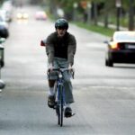 Fietser remt op een drukke straat tussen geparkeerde auto’s