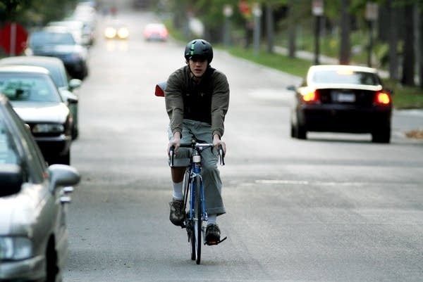 Fietser remt op een drukke straat tussen geparkeerde auto’s