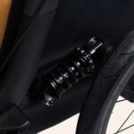 Close-up van een zwarte schokdemper bij het wiel van een fietskar
