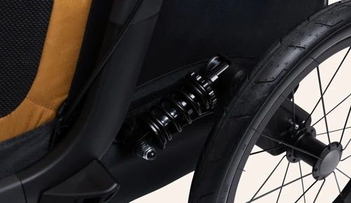 Close-up van een zwarte schokdemper bij het wiel van een fietskar